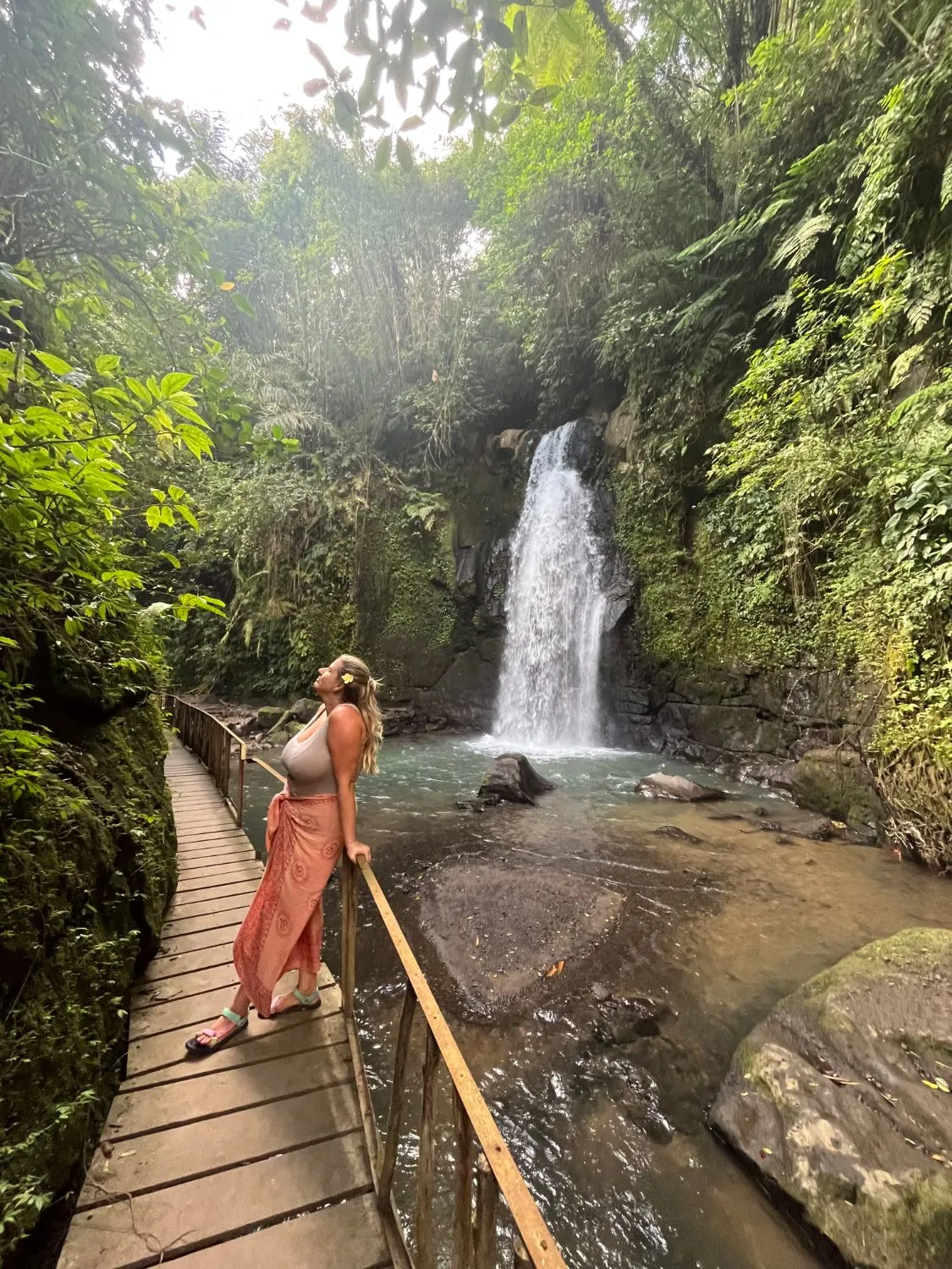 Carol en una pasarela frente a una cascada en la selva