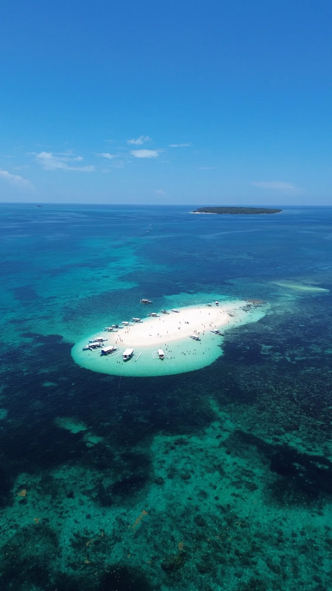 Isla de arena blanca rodeada de aguas turquesas en Filipinas, vista con dron